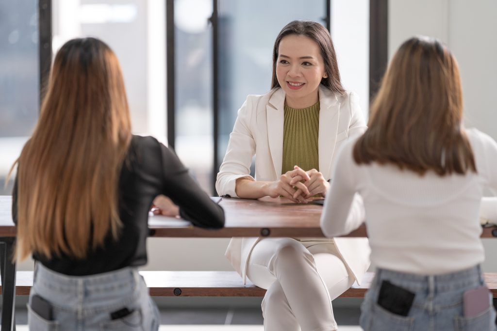 Horizontal shot of two Asian beautiful females meeting with their tutor