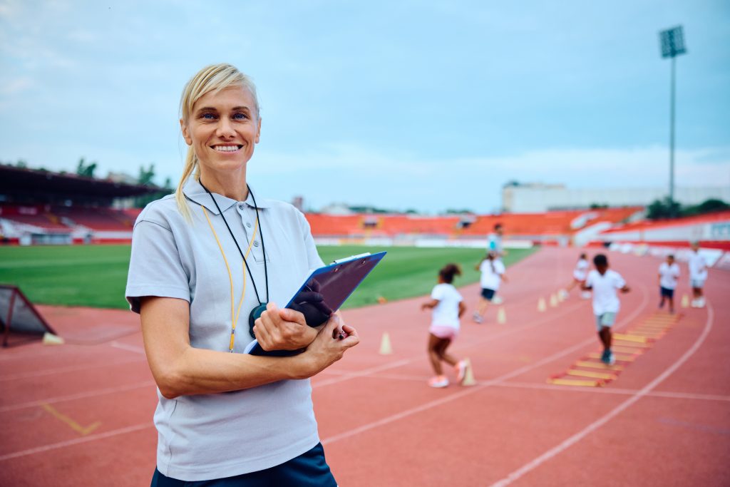 Portrait of happy physical education teacher at the stadium looking at camera.